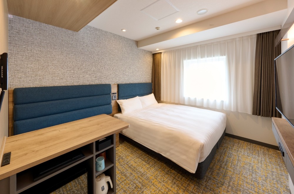 A bed and a spacious deskin the Viainn Double Room at  Via Inn Shinagawa-Oimachi