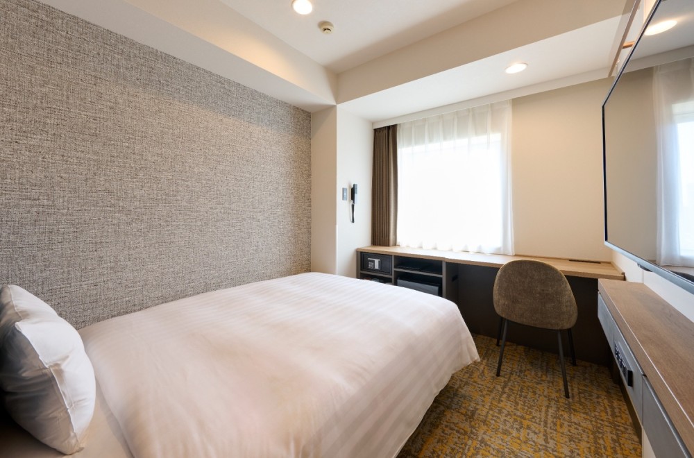 The bed and spacious desk in the Standard Single A room at Via Inn Shinagawa-Oimachi