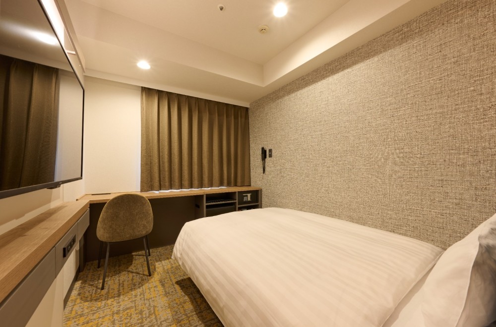 The bed and spacious desk in the Standard Single B room at Via Inn Shinagawa-Oimachi