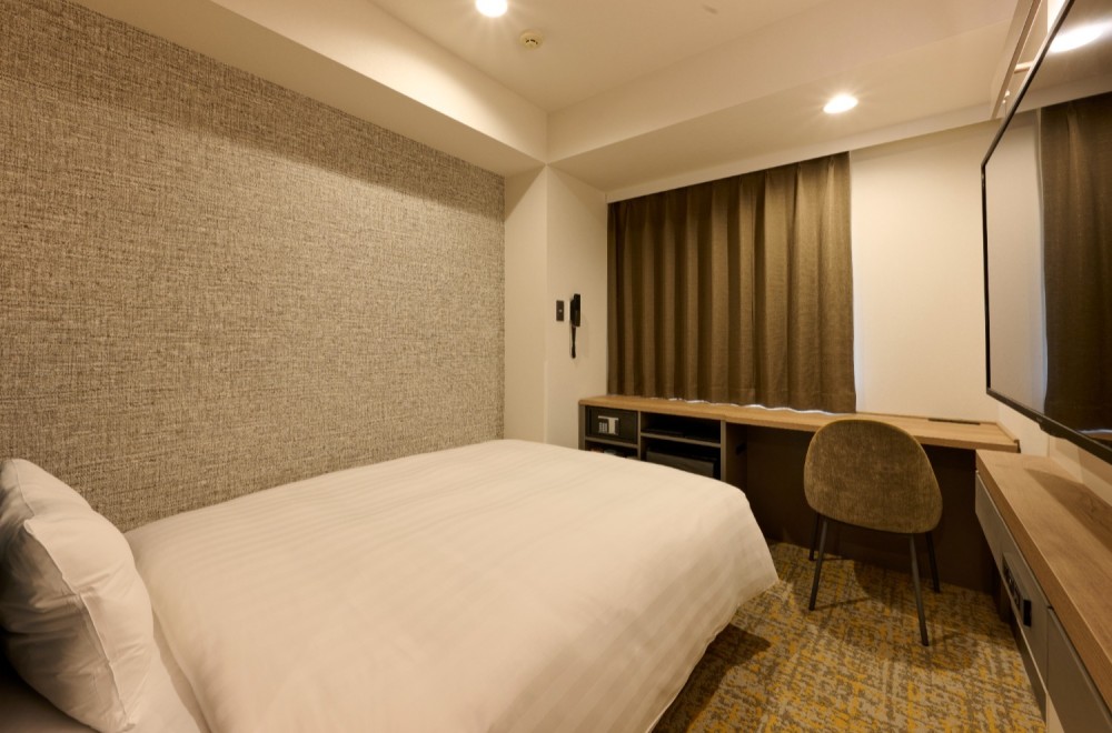 The bed and spacious desk in the Standard Single A room at Via Inn Shinagawa-Oimachi